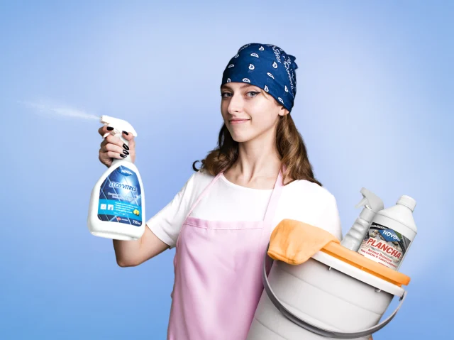 Gamme Novo Surfaces - femme de ménage avec des produits de nettoyage dans les mains sur fond bleu Gamme Novo Surfaces - femme de ménage avec des produits de nettoyage dans les mains sur fond bleu