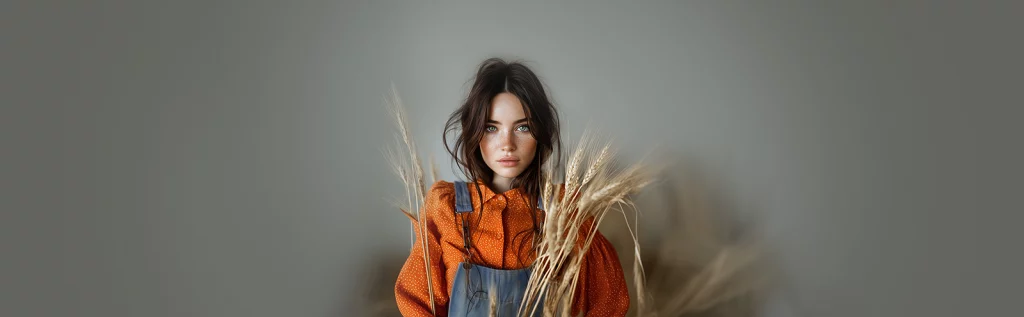 Gamme Pyrox - Femme brune sur fond neutre habillée en salopette en jean et chemise orange avec des blés devant elle